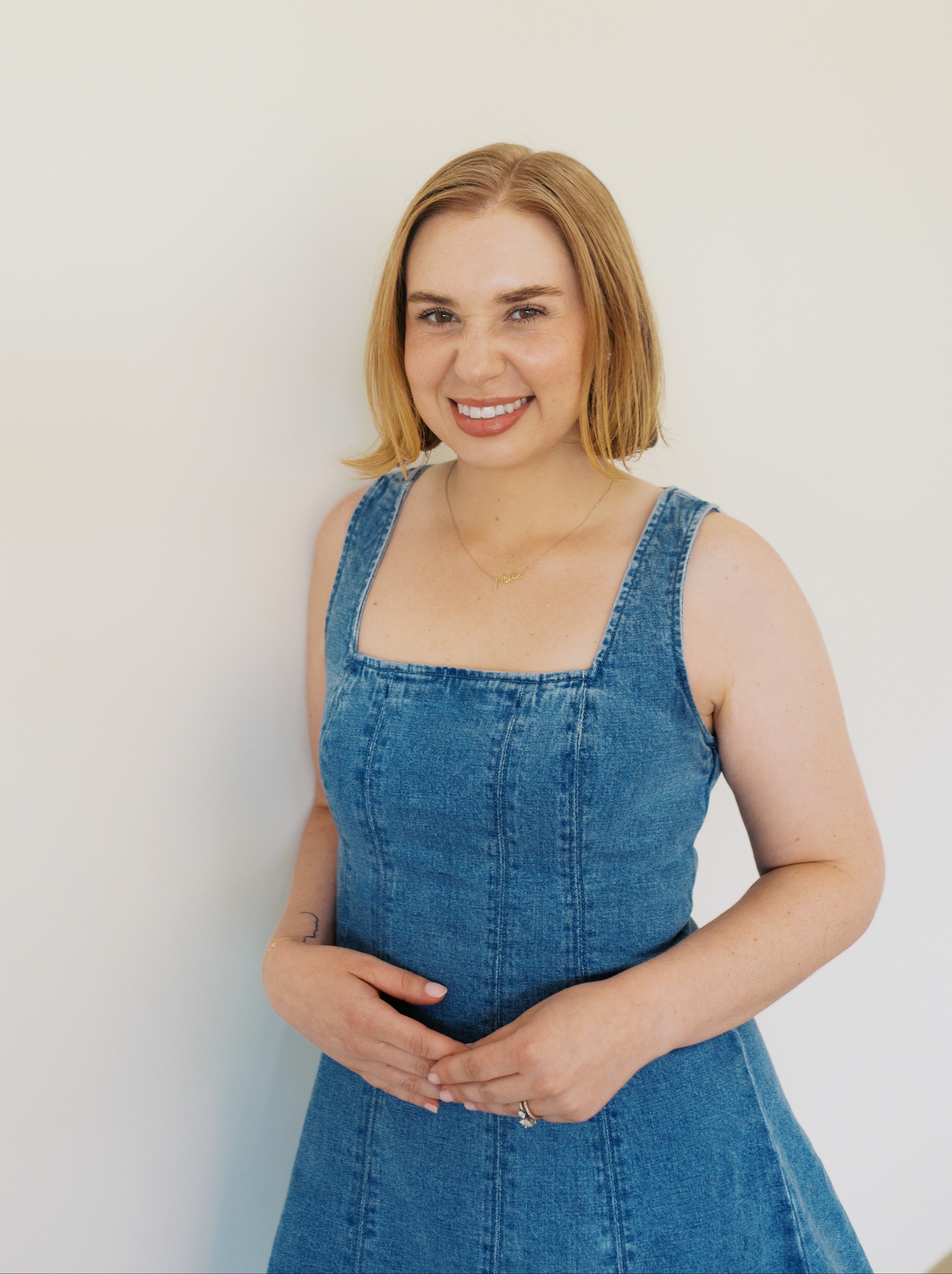 Woman wearing a blue denim dress against a plain background